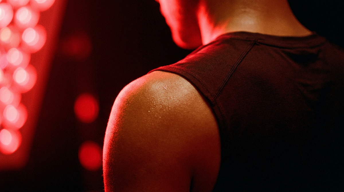 Schouder en bovenrug na inspanning, warm oplichtend in rood licht