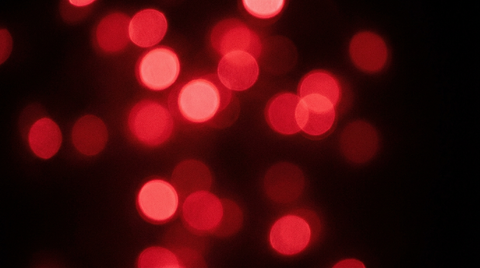 Rode lichtpunten volledig buiten focus als abstracte bokeh tegen een zwarte achtergrond