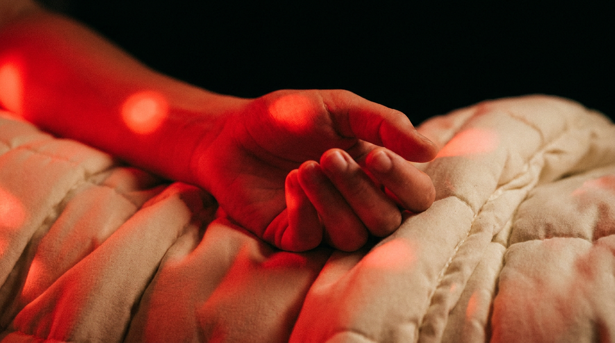 Ontspannen hand op een dikke opgevouwen deken, warm oplichtend onder fel rood licht