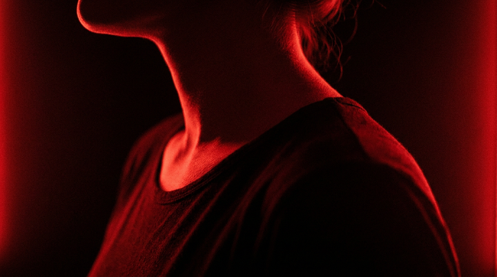 Nek en schouders van opzij in rood licht, illustratie bij het verschil tussen een infrarood paneel en een roodlicht paneel