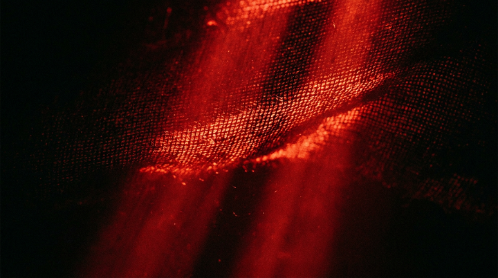 Rode lichtstralen die door de weving van textiel schijnen